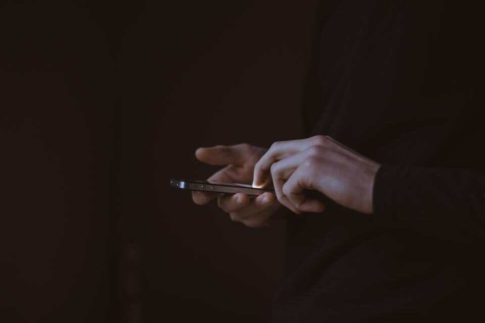 Self-hosted team messaging hands typing a message on a phone in a dark room