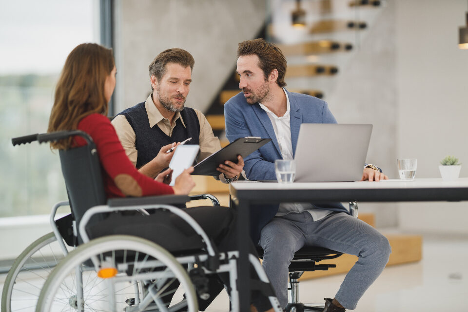 wheelchair user working with colleagues at a laptop